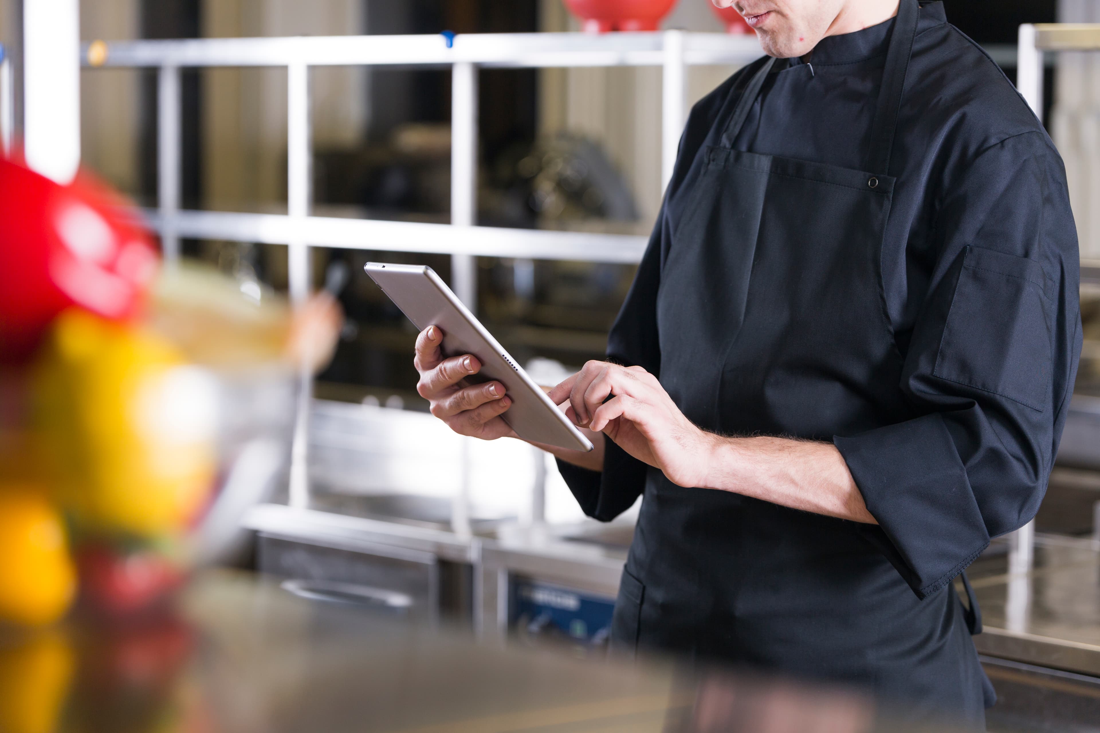 Restaurant chef reviewing data on a tablet in a professional kitchen
